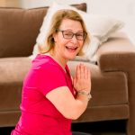 Woman in pink shirt with hands in prayer.
